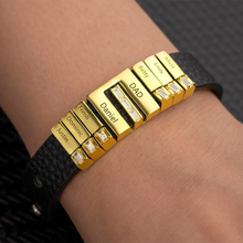 Cargar imagen en el visor de la galería, La Pulsera de cuero personalizada con nombres es negra, con dijes dorados rectangulares grabados con nombres-Alicia, Emily, Betty, DAD, Daniel, Ernst, Dominic y Justin-algunos con piedras claras; un regalo único para papá.