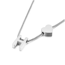 Cargar imagen en el visor de la galería, A pulsera de tobillo con inicial en color plateado, decorada con un charm en forma de letra H y un pequeño corazón sobre una cadena tipo box, mostrada sobre fondo blanco.