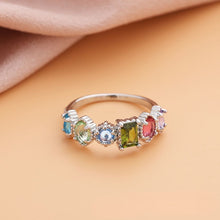 Cargar imagen en el visor de la galería, El Anillo con piedras natales en plata incluye cinco gemas de colores (azul, verde, rosa, celeste y lila) en engastes decorativos, sobre fondo durazno; un regalo ideal para el Día de las Madres.