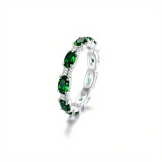 Anillo Energía Zodiacal con piedra de nacimiento: un anillo de plata con varias piedras energéticas verdes ovaladas engastadas en banda continua, expuesto sobre fondo blanco con sombra suave.