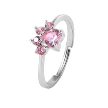 Cargar imagen en el visor de la galería, El Anillo Patita rosa en color plateado luce una gema central en forma de corazón rosa, rodeada de pequeñas piedras rosadas-ideal como recuerdo de mascota o regalo para amantes de mascotas.