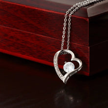 Cargar imagen en el visor de la galería, Collar Amor eterno: Un collar colgante de plata en forma de corazón con una gema redonda central y pequeños diamantes, elegantemente drapeado sobre un joyero de madera pulida-un regalo perfecto para mujer.