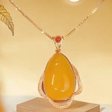 Cargar imagen en el visor de la galería, El Collar amuleto de piedra ágata amarilla es un diseño retro con un colgante ovalado de ágata amarilla enmarcado en oro texturizado y una pequeña piedra roja, irradiando energía positiva sobre fondo beige.