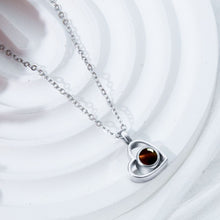 Cargar imagen en el visor de la galería, El Collar de corazón con foto, en color plateado, es ideal para collares personalizados y guardar recuerdos especiales. Presentado sobre un fondo blanco texturizado.