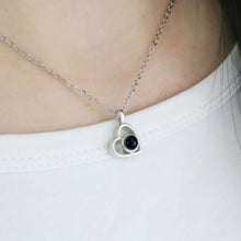 Cargar imagen en el visor de la galería, El collar de corazón con foto, con piedra oscura central, es perfecto para guardar recuerdos especiales o como uno de nuestros exclusivos collares personalizados. Ideal para llevar sobre una camisa blanca.