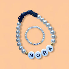 Cargar imagen en el visor de la galería, El Collar de cuentas personalizado para mascotas + Pulsera gratis incluye ambos con el nombre NORA en cuentas sobre fondo durazno. El collar tiene cuentas grandes y broche negro, ideal como regalo original para amantes de mascotas.