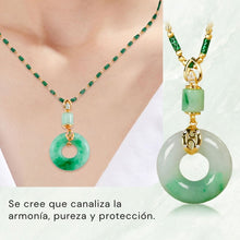 Cargar imagen en el visor de la galería, Primer plano de una persona que lleva el "Collar de piedra jade esmeralda natural", un colgante redondo de jade verde en forma de donut con detalles dorados. Texto en español debajo: "Se cree que este collar canaliza armonía, pureza y protección".