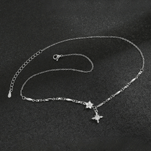 Cargar imagen en el visor de la galería, El collar Destello de estrella es un delicado collar de plata con una fina cadena, pequeños eslabones decorativos y un colgante en forma de estrella acentuado con piedras brillantes, que se muestra sobre una superficie negra texturizada.