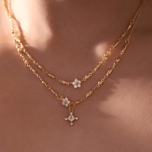 Cargar imagen en el visor de la galería, Un primer plano del cuello de una persona muestra collares de cadena de oro en capas, incluido el Collar Destello de estrella, con cada colgante adornado con pequeñas piedras brillantes sobre una piel suavemente iluminada.