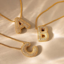 Cargar imagen en el visor de la galería, Se muestran dos collares Collar Inicial Bubble -con grandes colgantes A, B y C texturizados con incrustaciones de cristales- sobre una superficie beige. ¡Lévate 2 por el precio de 1! Elige tu inicial para un regalo elegante y personalizado.