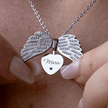 Cargar imagen en el visor de la galería, Una persona sostiene el Collar "Mi ángel guardián" personalizable (Oferta 2X1) con dijes de alas de ángel y un corazón grabado con el nombre Marie y un pequeño símbolo de corazón.