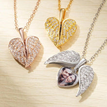 Cargar imagen en el visor de la galería, El collar personalizado con foto en forma de corazón incluye tres colgantes alados en forma de corazón en oro, oro rosa y plata con piedras brillantes. El colgante plateado se abre para mostrar la foto de una pareja sonriente.