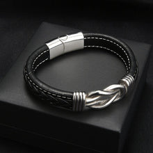 Cargar imagen en el visor de la galería, La Pulsera con nudo infinito - A mi hijo es una pulsera de piel negra con costuras blancas, detalle trenzado, cierre plateado y nudo decorativo, perfecta como regalo para hijo o como pulsera especial madre e hijo.