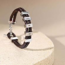 Cargar imagen en el visor de la galería, La Pulsera de cuero para Papá en color marrón cuenta con trenzado y cuentas rectangulares plateadas grabadas con nombres y NUMBER ONE DAD, sobre una piedra beige clara; un regalo ideal para hombre.