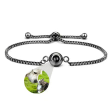 Cargar imagen en el visor de la galería, Pulsera negra ajustable Pulsera Recuerdo eterno con un charm redondo que, al ampliarlo, revela la imagen de un perro tocando suavemente las narices con un gatito sobre la hierba verde.