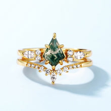 Cargar imagen en el visor de la galería, El Set de anillos piedra ágata verde destaca por su diseño simétrico y elegante, con una piedra central de ágata verde corte marquesa rodeada de pequeños diamantes sobre fondo azul claro.