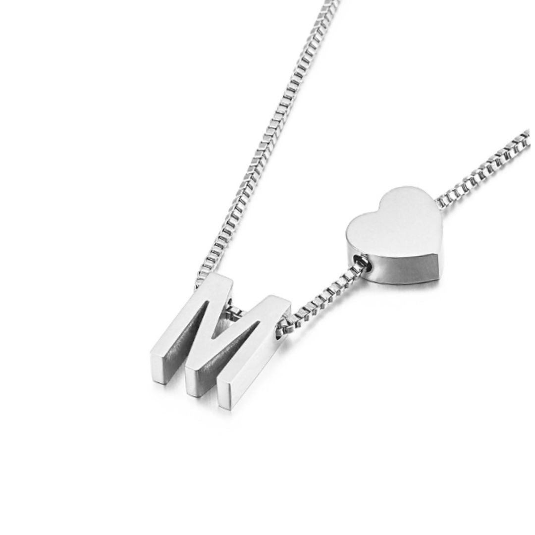Un collar de cadena de caja de plata con un charm de corazón y dos colgantes M combina a la perfección con la pulsera de tobillo con inicial plateado para un look coordinado.