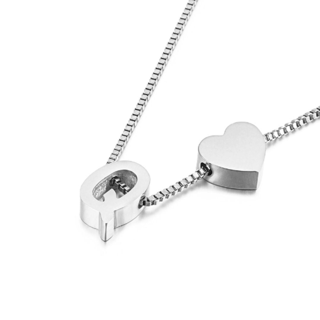 Un collar de plata con dos colgantes -un corazón y una cerradura en forma de Q- cuelga de una sencilla cadena de caja; combínalo con la Pulsera de tobillo con inicial en plateado para un estilo único.