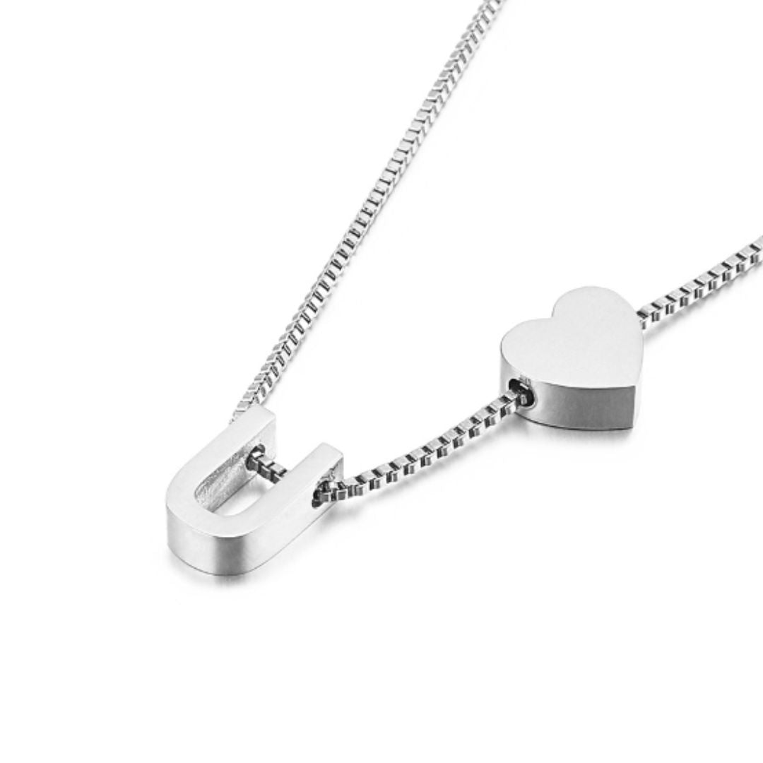 Un collar de plata con una cadena minimalista y dos colgantes -un corazón y un imán- combina a la perfección con el Pulsera de tobillo plateado con inicial para un look coordinado y elegante.
