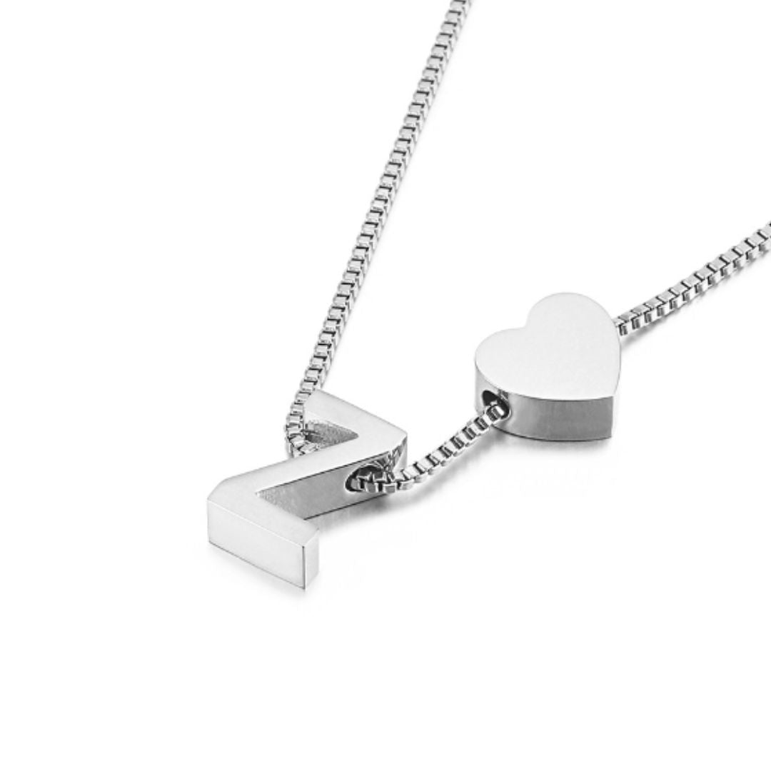 A pulsera de tobillo con inicial plateada presenta dos dijes: una letra Z mayúscula y un corazón sólido, ambos en acabado pulido, mostrando un diseño elegante sobre fondo blanco.
