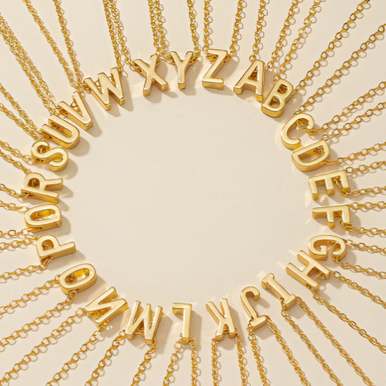 Pulsera de tobillo con inicial: Elegantes pulseras de tobillo doradas con colgantes del alfabeto dispuestos en círculo sobre beige, cada cadena irradiando hacia el exterior, perfectas para exhibir tu estilo único.