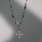 El collar Destello de estrella presenta dos colgantes en forma de estrella decorados con piedras claras, sobre un fondo gris claro suavemente iluminado.