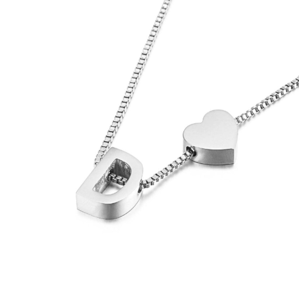 Un plateado "Pulsera de tobillo con inicial" luce una delicada cadena con un charm de letra D en bloque y un charm en forma de corazón uno al lado del otro, a modo de tobillera con inicial, sobre un fondo blanco.
