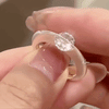 Primer plano de una mano sosteniendo el Anillo giratorio estelar, con un gran diamante redondo engastado en el centro que resalta su brillante gema y su banda pulida y ajustable.