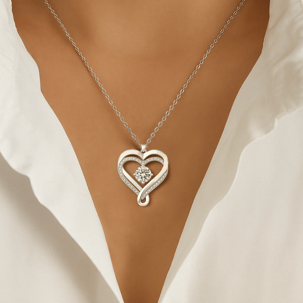 Una mujer con blusa blanca luce el "A mi esposa" - Collar corazón para siempre, un colgante de corazón de plata con diseño entrelazado, gema central brillante y detalles de cristal, perfecto como regalo para pareja.