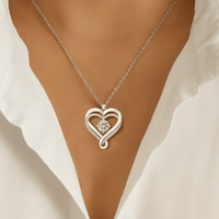 Una mujer con blusa blanca luce el "A mi esposa" - Collar corazón para siempre, un colgante de corazón de plata con diseño entrelazado, gema central brillante y detalles de cristal, perfecto como regalo para pareja.