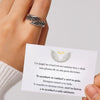 Una mano que lleva el Anillo Alas de Ángel sostiene una tarjeta con alas de ángel y un halo, mostrando un reconfortante mensaje en español sobre el apoyo, la fuerza y la guía de tu ángel de la guarda.