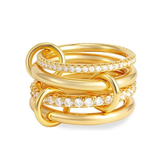 El Anillo apilable brillante es de oro, presenta bandas entrelazadas y algunas llevan circonitas cúbicas brillantes, creando un diseño elegante y sofisticado.