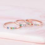 El Anillo con piedras de nacimiento personalizado, elaborado en oro rosa con gemas multicolores, brilla sobre suave mármol rosa: un regalo de ensueño para el Día de las Madres o un anillo con piedras de nacimiento en tonos pastel.