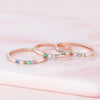 El Anillo con piedras de nacimiento personalizado, elaborado en oro rosa con gemas multicolores, brilla sobre suave mármol rosa: un regalo de ensueño para el Día de las Madres o un anillo con piedras de nacimiento en tonos pastel.