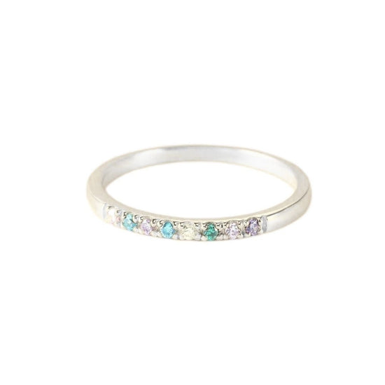 Un fino y plateado Anillo con piedras de nacimiento personalizado con una hilera de pequeñas gemas multicolores engarzadas a lo largo de la mitad superior, sobre un fondo blanco liso.