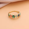 El Anillo con piedras natales de oro luce cinco gemas de colores-verde, rojo, dos celestes y azul oscuro-alineadas sobre fondo durazno y tela beige. Un regalo perfecto para el Día de las Madres.