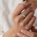 Primer plano de una mano que lleva el Anillo corazón del bosque, con delicados detalles de diamantes, sobre un fondo suave y neutro. La persona tiene las uñas cuidadas y la piel clara.