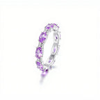 Anillo Energía Zodiacal con piedra de nacimiento: banda plateada con gemas ovaladas moradas, consideradas piedras energéticas, distribuidas uniformemente alrededor del anillo y expuestas sobre fondo blanco.