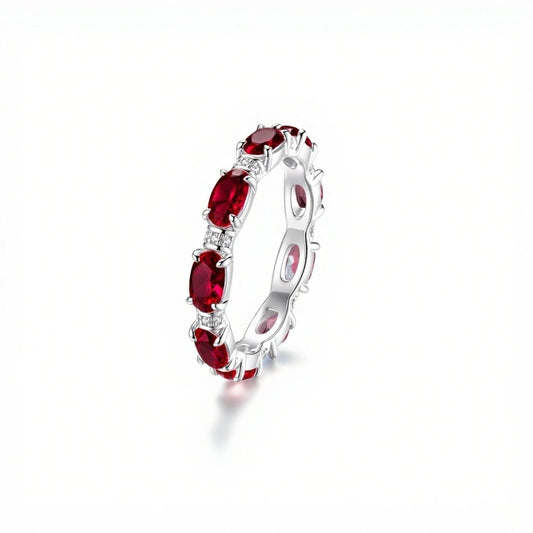 Anillo Energía Zodiacal con piedra de nacimiento: aro plateado con varias piedras energéticas rojas ovaladas distribuidas uniformemente sobre la banda, mostrado sobre fondo blanco.