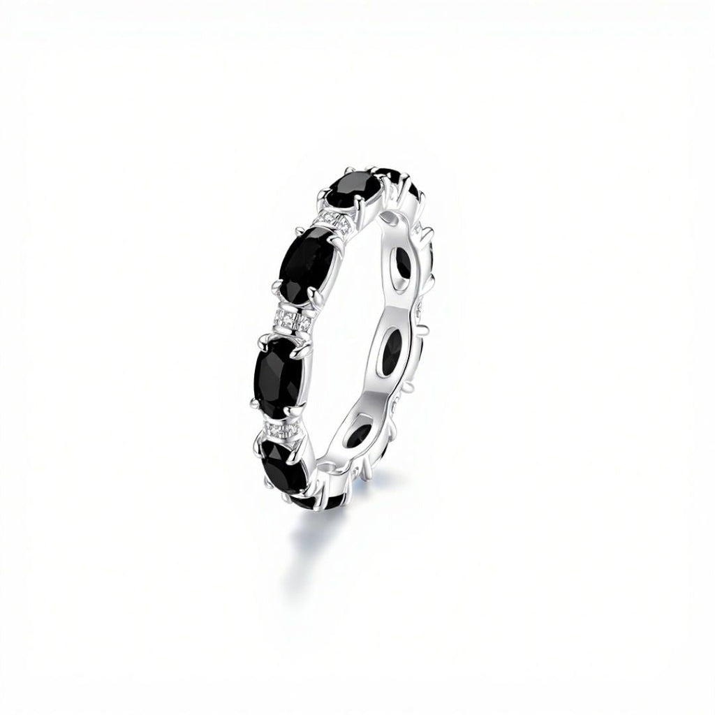 El Anillo Energía Zodiacal con piedra de nacimiento es un anillo espiritual de plata con piedras preciosas negras de talla ovalada y piedras transparentes sobre fondo blanco, ideal para los amantes de las piedras energéticas.