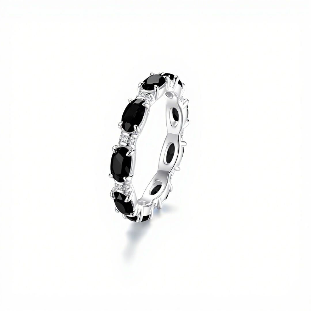 El Anillo Energía Zodiacal con piedra de nacimiento es un anillo espiritual de plata con piedras preciosas negras de talla ovalada y piedras transparentes sobre fondo blanco, ideal para los amantes de las piedras energéticas.
