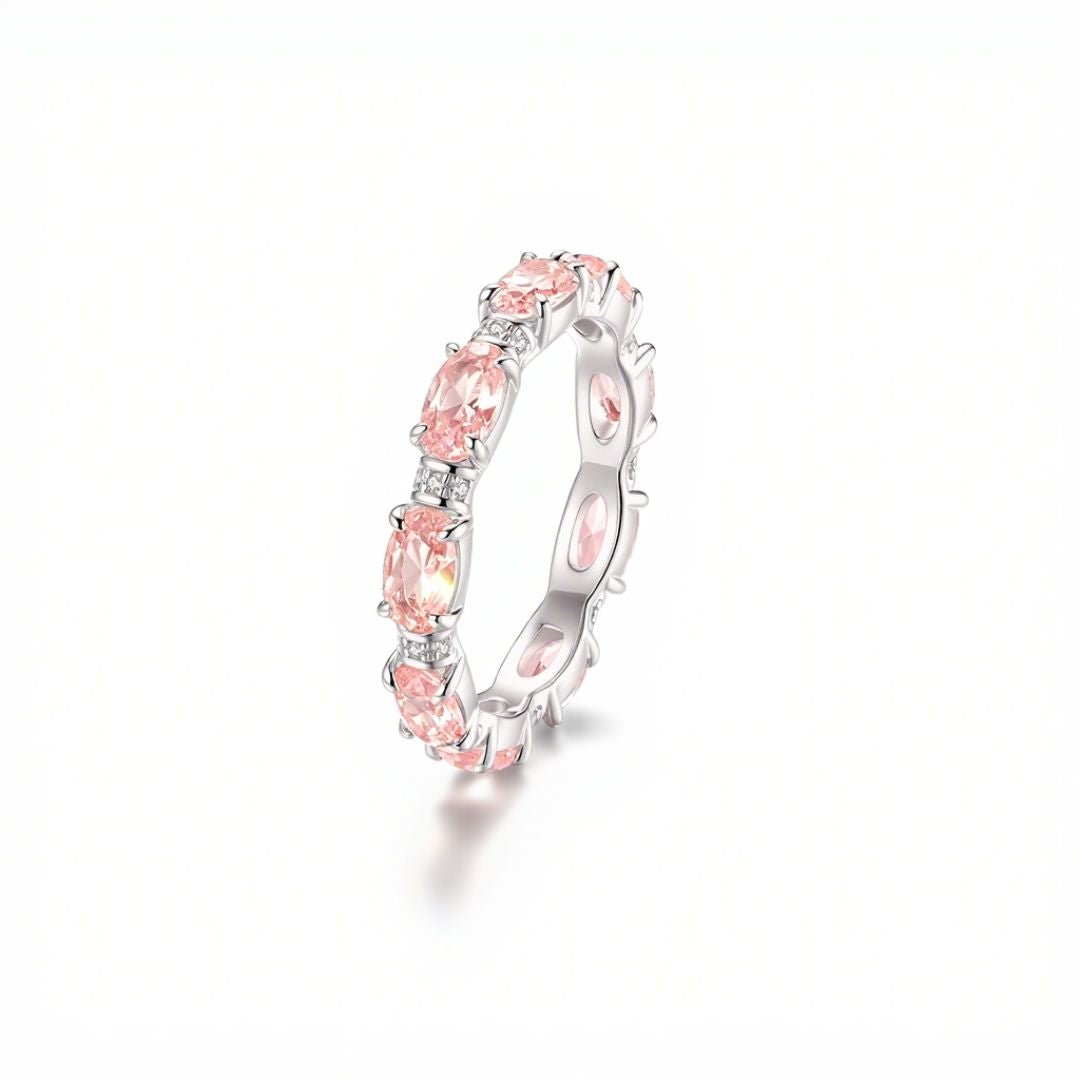 El Anillo Energía Zodiacal con piedra de nacimiento es un anillo de plata con múltiples piedras energéticas rosas de talla oval engastadas en un patrón continuo, sobre fondo blanco.