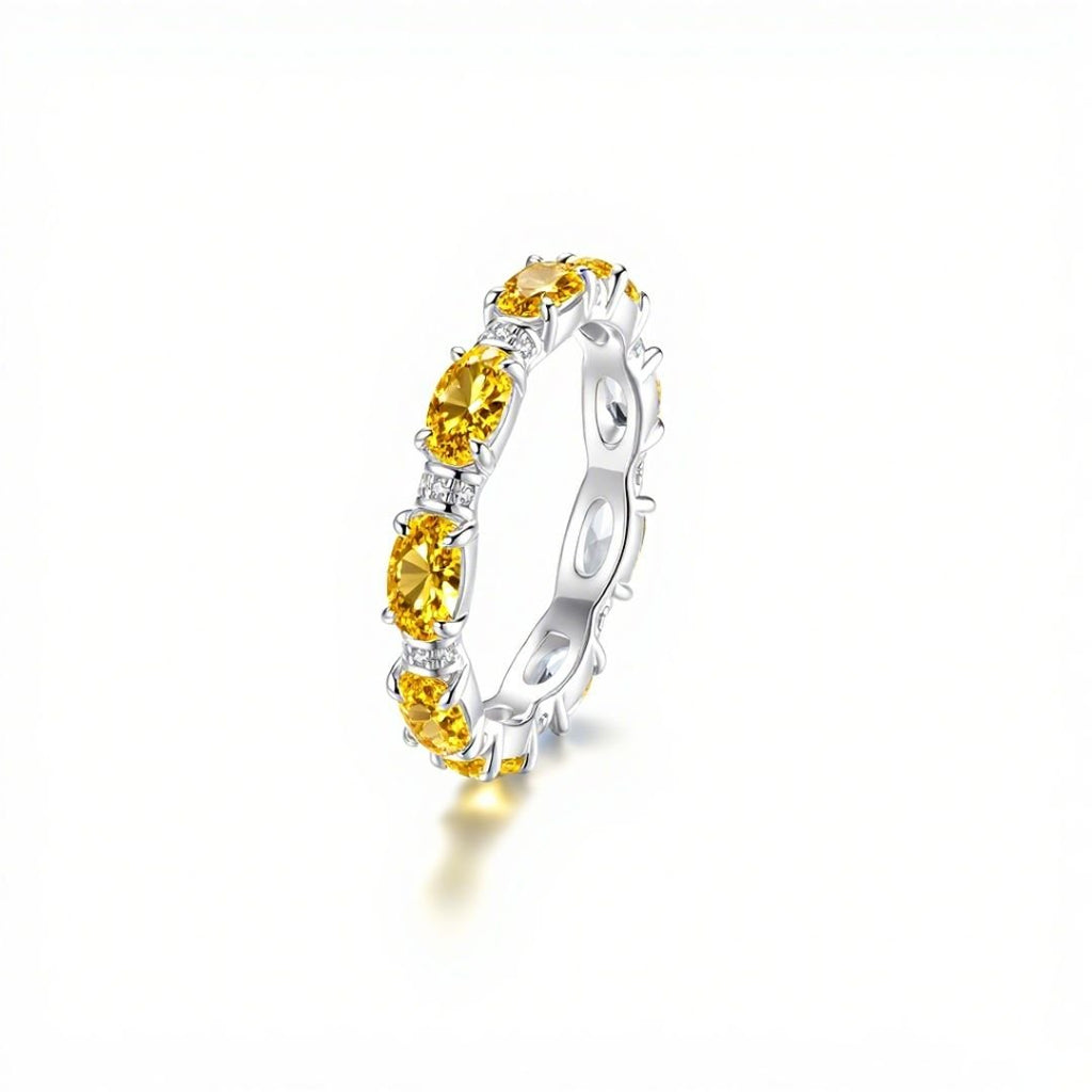 El Anillo Energía Zodiacal con piedra de nacimiento es un anillo de plata con gemas amarillas de talla ovalada engarzadas en garras, inspirado en la joyería espiritual y el poder de las piedras energéticas, que se muestra sobre un fondo blanco.
