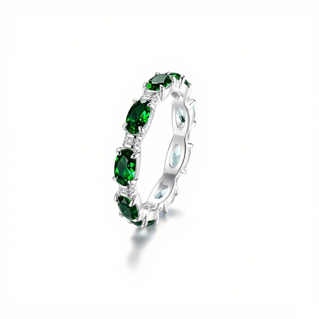 Anillo Energía Zodiacal con piedra de nacimiento: un anillo de plata con varias piedras energéticas verdes ovaladas engastadas en banda continua, expuesto sobre fondo blanco con sombra suave.