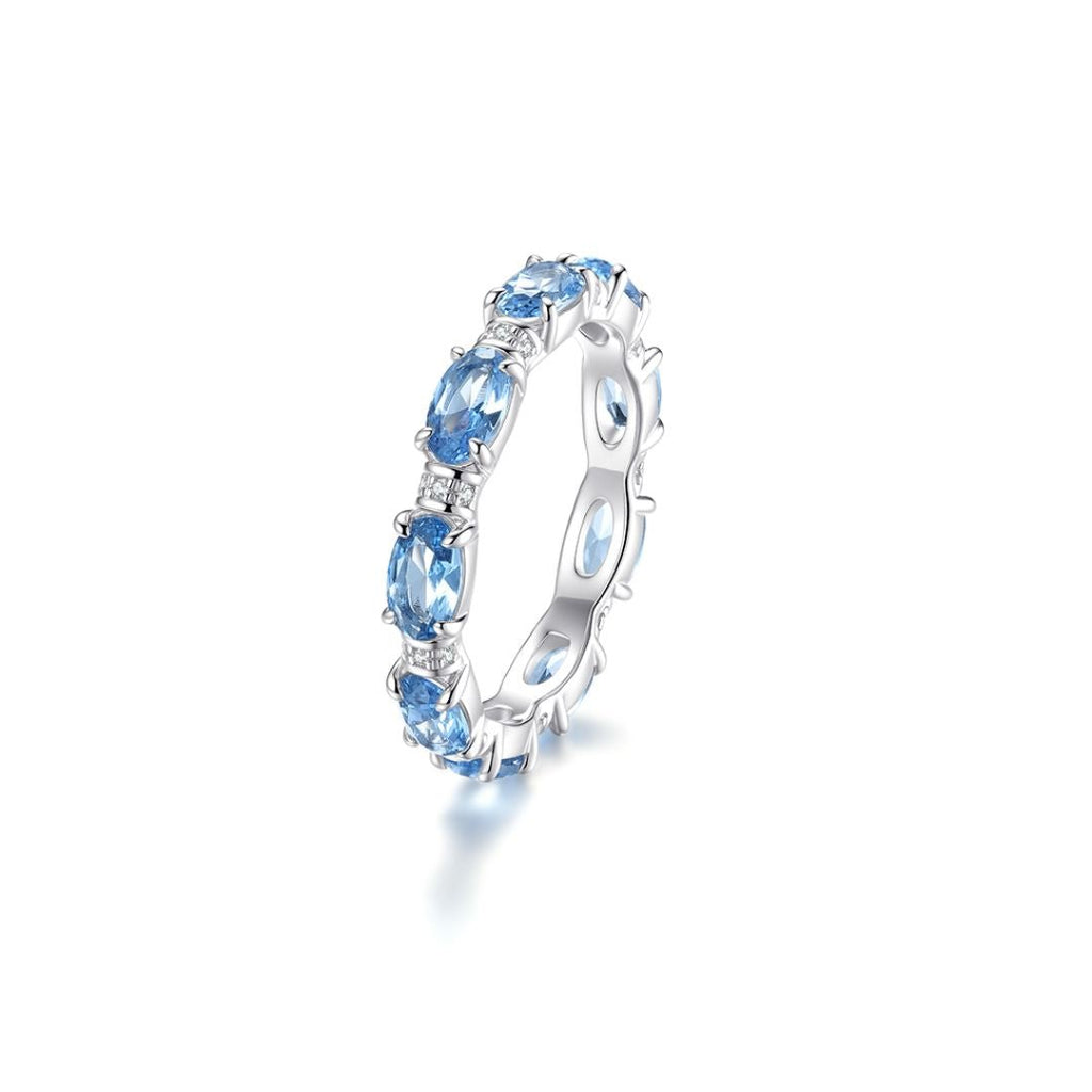 El Anillo Energía Zodiacal con piedra de nacimiento es un anillo de plata con una banda continua de piedras energéticas ovaladas de color azul claro, cada una separada por púas, perfecto para añadir joyería espiritual a tu estilo.
