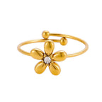 El Anillo Flor ajustable es un delicado anillo con una banda abierta de oro, cinco pétalos redondeados, una gema central transparente y dos pequeñas esferas de oro en los extremos para añadir encanto.