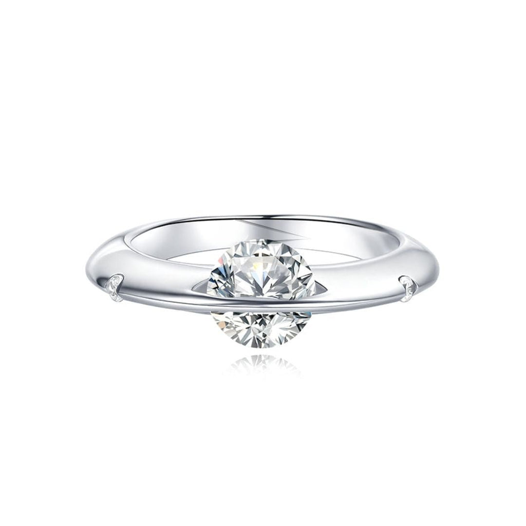 Anillo giratorio estelar: un anillo de plata ajustable con un diamante redondo sujeto por dos delicadas garras, que le dan un efecto flotante, sobre fondo blanco.