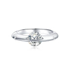 Anillo giratorio estelar: un anillo de plata ajustable con un diamante redondo sujeto por dos delicadas garras, que le dan un efecto flotante, sobre fondo blanco.