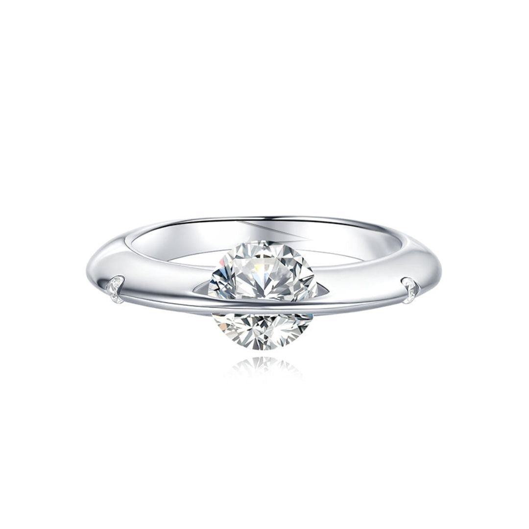 Anillo giratorio estelar: un anillo de plata ajustable con un diamante redondo sujeto por dos delicadas garras, que le dan un efecto flotante, sobre fondo blanco.
