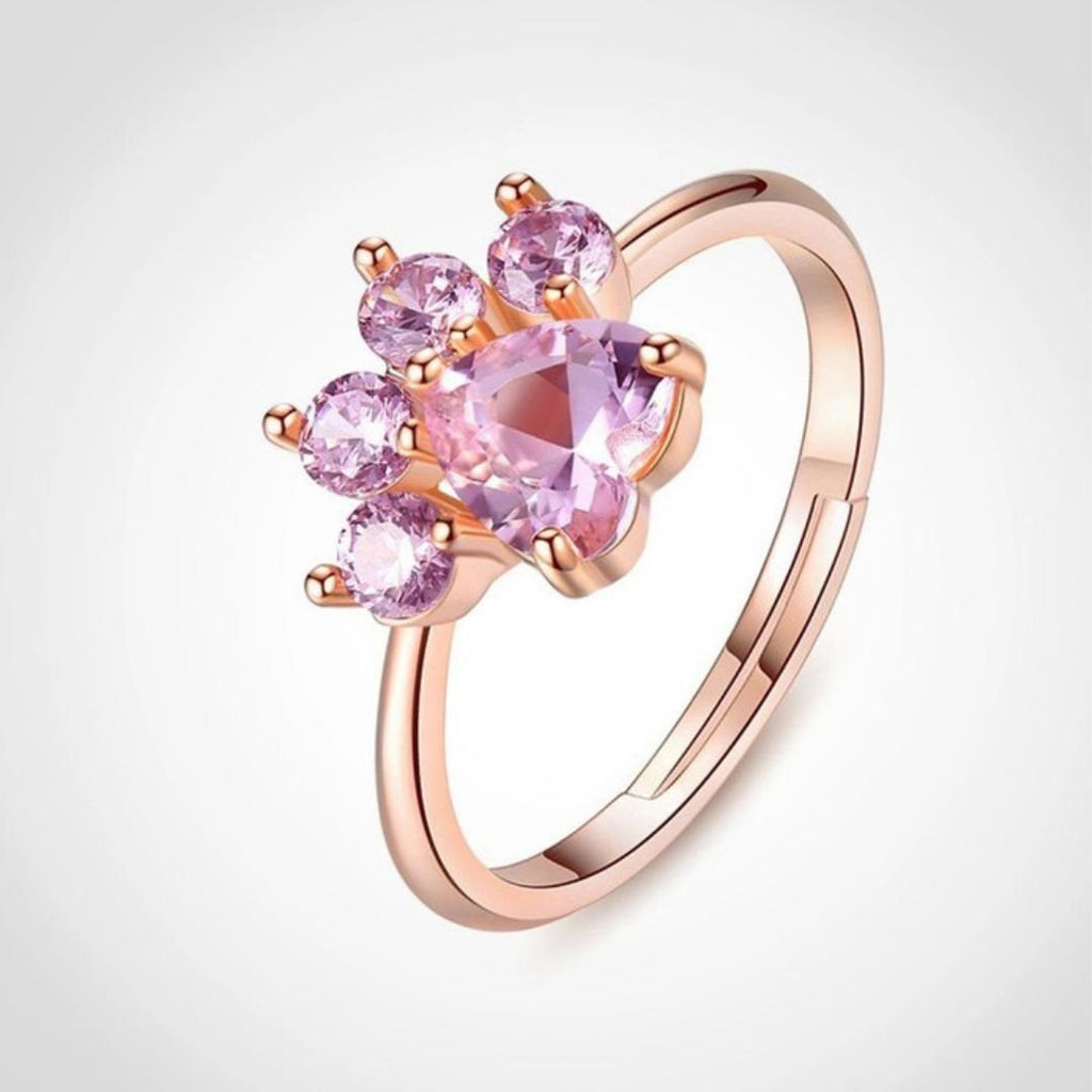 El Anillo Patita rosa es un anillo de oro rosa con cinco piedras preciosas rosas en un diseño con forma de pata: un centro en forma de corazón y cuatro dedos redondos. Perfecto para los amantes de las mascotas.